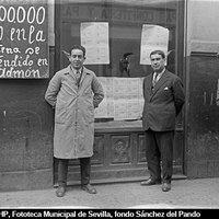 Administración de lotería de Miguel Escámez Arqueros. El propietario posando ante el escaparate de la calle Amor de Dios, 62 con el número premiado con el Tercer Premio. 1929 ©ICAS-SAHP, Fototeca Municipal de Sevilla, fondo Sánchez del Pando 