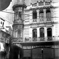 Vista de la fachada del Café de París en la esquina con la calle O'Donnell. El edificio de inspiración modernista, obra de Aníbal González (1904-1906) era lugar de reunión de la clase media y de la burguesía sevillana. En la primera planta albergaba un salón de billares. Como curiosidad durante los años de la Guerra Civil se le denominó Café de Roma. Su abandono acabó deteriorando la belleza de la fachada, siendo derribado a finales de la década de los años 60 del siglo XX. A la izquierda aún se aprecia la estrechez de la calle Campana antes del derribo del Café Novedades. 1905 ©ICAS-SAHP, Fototeca Municipal de Sevilla, fondo Caparró