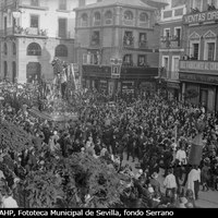 Paso del Cristo de las Cinco Llagas de la Hermandad de la Trinidad en el inicio de la carrera oficial. Al fondo la confitería La Campana, el estudio fotográfico del mismo nombre, la sombrerería Casa Sirio y la joyería Dalmás. ©ICAS-SAHP, Fototeca Municipal de Sevilla, fondo Serrano