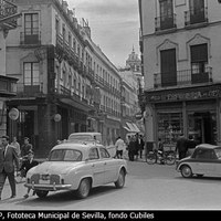 Intersección de las calles que confluyen en la Campana: Velázquez y O´Donnell. A la izquierda el rótulo de Almacenes Iñiguez, de paños y sedas y a la derecha la perfumería y mercería de Pedro Gómez. Un “biscuter” de dos plazas se dirige hacia la calle O´Donnell. 1961 ©ICAS-SAHP, Fototeca Municipal de Sevilla, fondo Cubiles